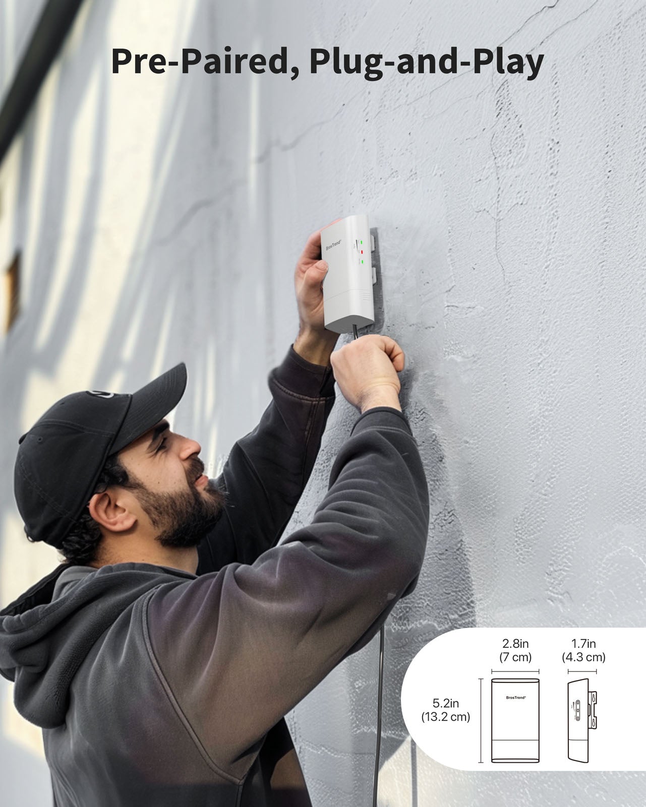 A Smiling Man is Standing in Front of a Wall and Mounting His WiFi Bridge Which Supports Plug and Play and Is Pre-Paired by Default It Can Be Powered via Included Passive PoE Injector or DC Power Adapter